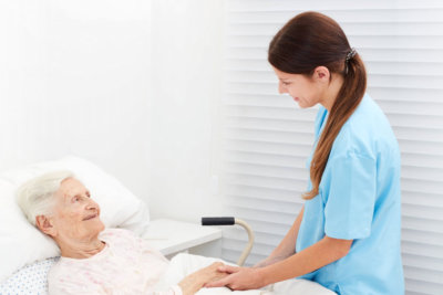 female nurse checking condition of an elderly woman in bed