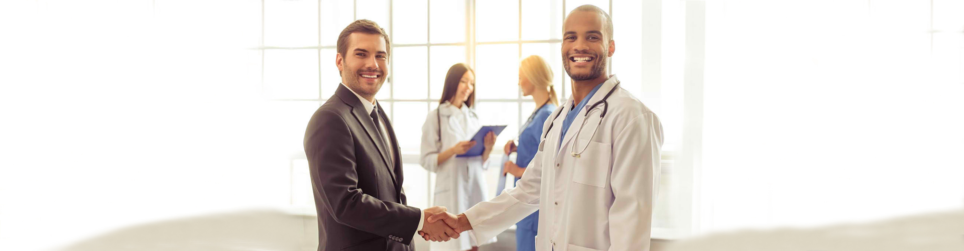 man in business attire shaking hands with a healthcare staff